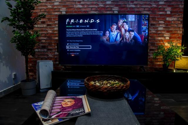 La televisión de pantalla plana muestra una sinopsis de un episodio de Friends en Netflix en una habitación acogedora