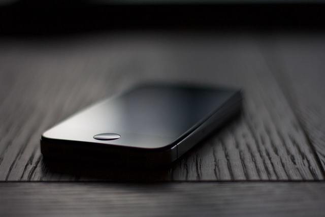 Iphone negro con la pantalla apagada sobre un fondo oscuro